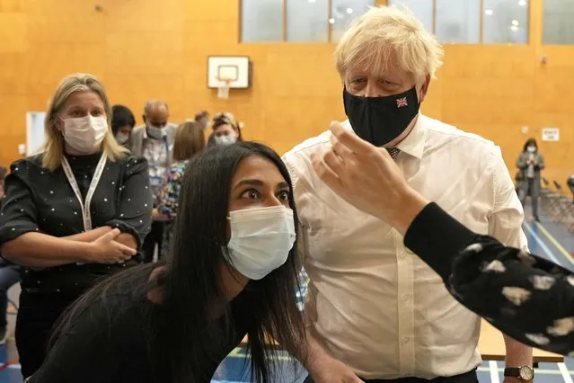 British Prime Minister Boris Johnson watches as staff dilute a dose of the Pfizer vaccine before administering it as he visits a COVID-19 vaccination centre at Little Venice Sports Centre, in London, Friday, October 22, 2021. (Photo by Matt Dunham/AP Photo/Pool)