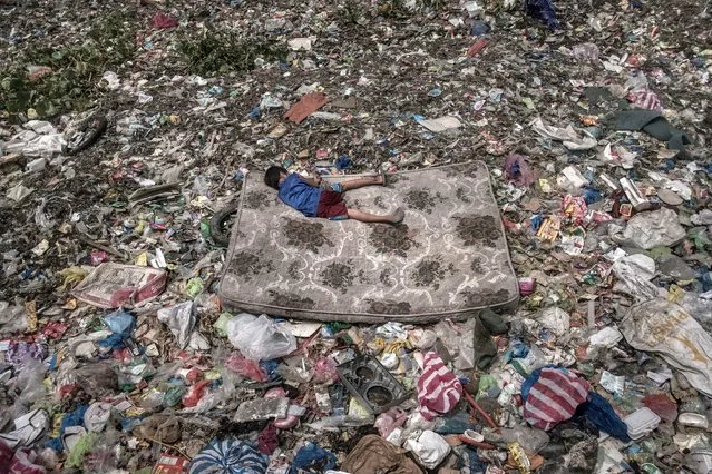 A child lying on a mattress surrounded by a garbage patch floating on the Pasig River in Manila, Philippines. (Photo by Mario Cruz/World Press Photo 2019)