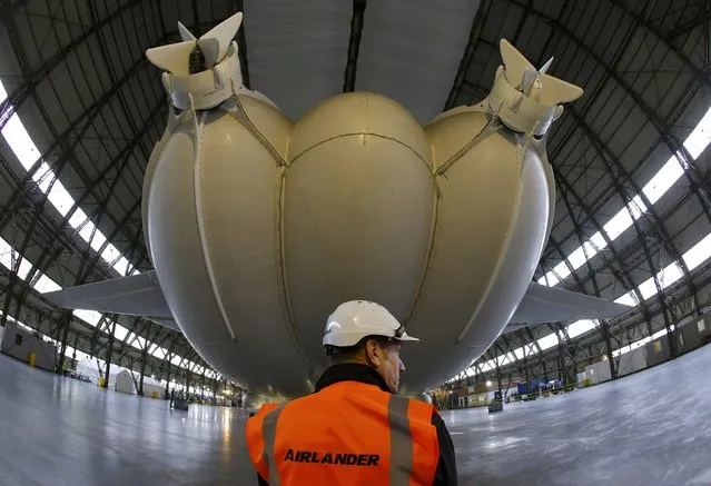 A worker stands under the Airlander 10 hybrid airship during its unveiling in Cardington, Britain March 21, 2016. (Photo by Darren Staples/Reuters)