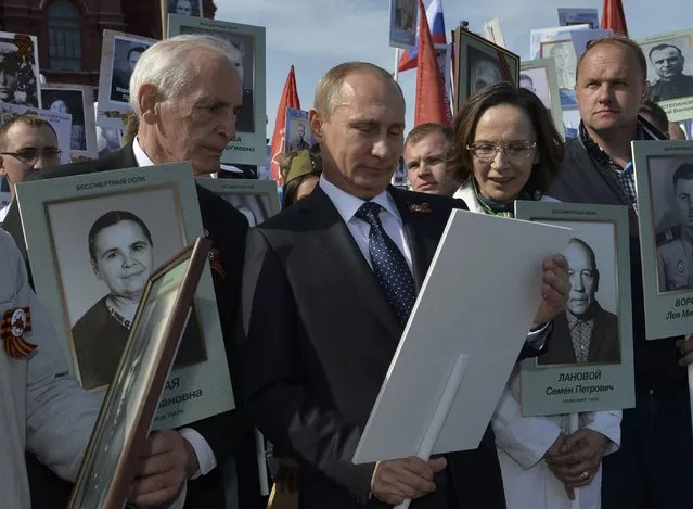Russian actor Vasily Lanovoy (L) speaks with President Vladimir Putin (C) holding a portrait of his father, war veteran Vladimir Spiridonovich Putin during the Immortal Regiment march on the Red Square in Moscow, Russia, May 9, 2015. (Photo by Reuters/Host Photo Agency/RIA Novosti)