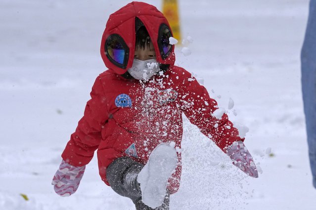 A child kicks up fresh snow in Beijing, China, Sunday, November 7, 2021. An early-season snowstorm has blanketed much of northern China including the capital Beijing, prompting road closures and flight cancellations. (Photo by Ng Han Guan/AP Photo)