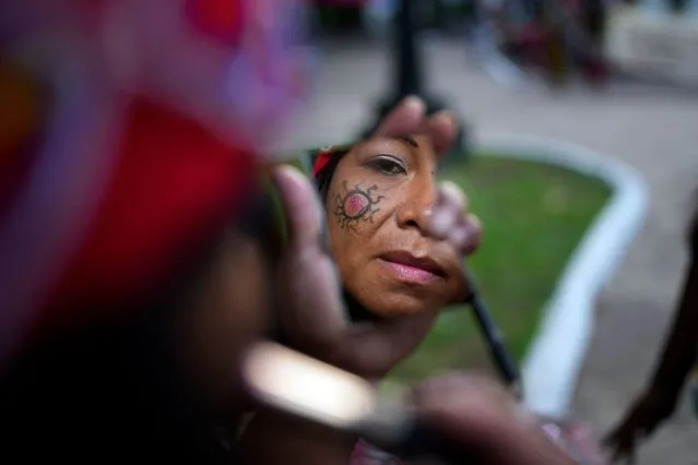 A Maka Indigenous woman puts on make-up before protesting for the recovery of ancestral lands in Asuncion, Paraguay, February 28, 2024. Her protest group is denouncing that the government has built a bridge on their land in El Chaco's Bartolome de las Casas. (Photo by Jorge Saenz/AP Photo)