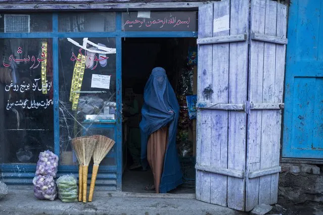 An Afghan woman wearing a burka exits a small shop in Kabul, Afghanistan, Sunday, December 5, 2021. Women's rights activists in the Afghan capital of Kabul insisted Sunday they would continue fighting for their right to education, employment and participation in Afghan political and social life, and said a recent Taliban decree banning forced marriage was not enough to address the issue of women's rights. (Photo by Petros Giannakouris/AP Photo)