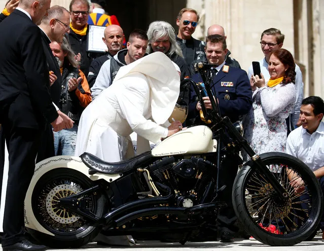 Pope Francis signs a Harley Davidson motorbike of the Christian motorcycle group “Jesus Biker” as his cape is blown by a gust of wind during the weekly general audience at the Vatican, May 29, 2019. (Photo by Yara Nardi/Reuters)