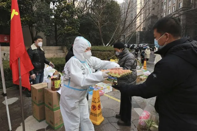 A community volunteer hands over eggs to a buyer at a temporary food store to provide supplies to residents outside a residential block in Xi'an city in northwest China's Shaanxi province Monday, January 03, 2022. Authorities in the northern Chinese city of Xi'an say they can provide food, health care and other necessities for the roughly 13 million under an almost two-week old lockdown. But some residents describe difficulties obtaining supplies and frustration and the economic impact on the city that is home to the famed Terracotta warriors, along with major industries. (Photo by Chinatopix via AP Photo)