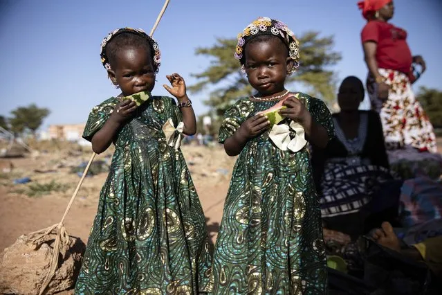 Twins eat slices of watermelon Thursday November 25, 2021 at the Patte d'Oie district of Ouagadougou, Burkina Faso, where mothers of twins come to beg on the road. In Burkina Faso, a country with a strong belief in the supernatural, twins are regarded as children of spirits whose mothers were specially selected to bear them. (Photo by Sophie Garcia/AP Photo)