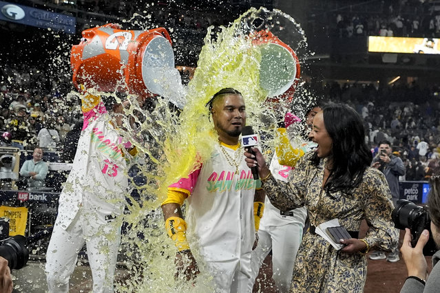 San Diego Padres' Luis Arraez is doused by teammates Manny Machado, left, and Fernando Tatis Jr. after hitting a walk-off single during the ninth inning of a baseball game against the Los Angeles Dodgers, Friday, May 10, 2024, in San Diego. The Padres won, 2-1. (Photo by Gregory Bull/AP Photo)