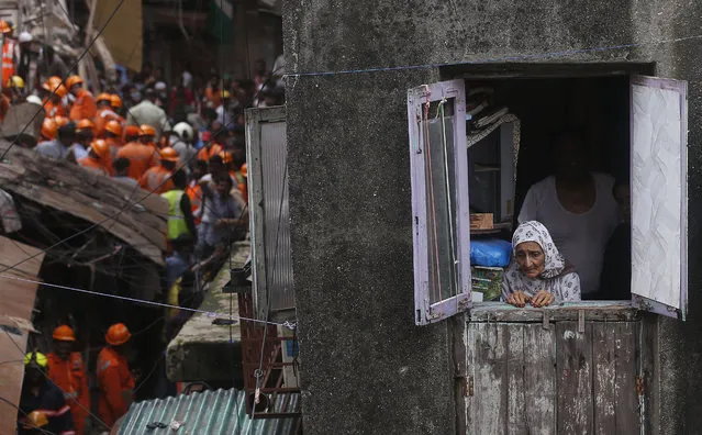 A woman looks from a window as rescuers work at the site of a building that collapsed in Mumbai, India, Tuesday, July 16, 2019. (Photo by Rafiq Maqbool/AP Photo)