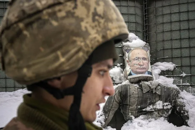 A Ukrainian serviceman speaks, backdropped by a bullet riddled effigy of Russian President Vladimir Putin, during a media interview at a frontline position in the Luhansk region, eastern Ukraine, Tuesday, February 1, 2022. Russia accused the West of “whipping up tensions” over Ukraine and said the U.S. had brought “pure Nazis” to power in Kyiv as the U.N. Security Council held a stormy and bellicose debate on Moscow's troop buildup near its southern neighbor. (Photo by Vadim Ghirda/AP Photo)