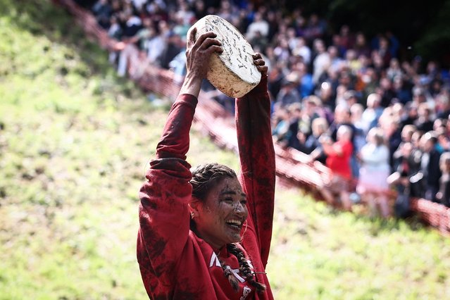 Winner of one the women's races Abby Lamp celebrates after competing in the annual Cooper's Hill cheese rolling competition near the village of Brockworth, Gloucester, in western England, on May 27, 2024. The annual Cooper's Hill Cheese Rolling involves competitors chasing an eight pound Double Gloucester cheese down a steep hill. (Photo by Henry Nicholls/AFP Photo)