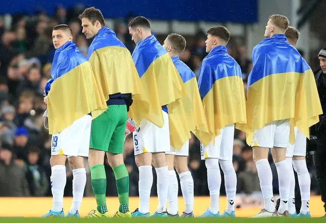 Everton's Ukrainian defender Vitaliy Mykolenko (L) and teammates stand draped in national flags of Ukraine ahead of the English FA Cup fifth round football match between Everton and Boreham Wood at Goodison Park in Liverpool, north west England on March 3, 2022. One million refugees have fled Ukraine in the week since Russia's invasion, the United Nations said Thursday, warning that unless the onslaught ended immediately, millions more were likely to flee. (Photo by Lindsey Parnaby/AFP Photo)