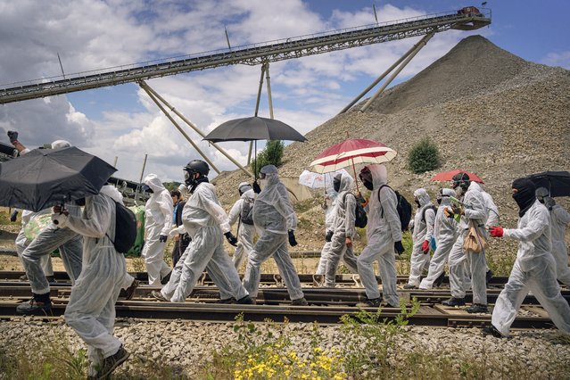 Environmental militants from Extinction Rebellion (XR) and “Stop Gravel” walk on the railway tracks at the Malet gravel pit during an action against site's operation, as they believe it is dangerous for the environment, at the camp near the Malet gravel pit, in Le Vernet, on June 1, 2024. Several hundred environment activists called by Extinction Rebellion and local collectives, forced the gates of a gravel pit and damaged buildings and vehicles to protest against the exploitation of the site, which they said was dangerous for the environment, AFP noted, in La Vernet, on June 1, 2024. (Photo by Idriss Bigou/AFP Photo)