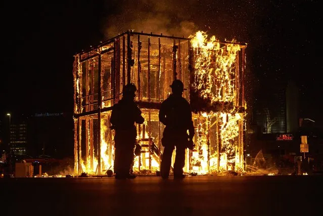 Las Vegas firefighters watch the controlled burn of the Life Cube, Saturday, April 2, 2016, in Las Vegas. Artist Scott Cohen created the project, a build-and-burn art installation, over the course of several weeks before burning it down. (Photo by John Locher/AP Photo)