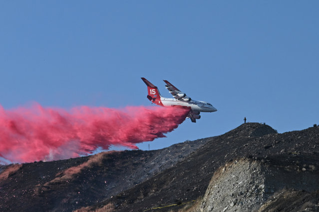 A plane drops flame retardant on a scorched hillside at the Poppy Fire on July 10, 2024 in Santa Clarita, Los Angeles County, California where temperatures reached over 101 degrees Fahrenheit (38 degrees Celsius). A record-breaking heat wave continued to grip the western United States on July 9, smashing records and endangering lives with little relief in sight. .Approximately 162 million people – nearly one-half of the US population – were living in areas under active heat warnings, according to the National Weather Service. (Photo by Robyn Beck/AFP Photo)