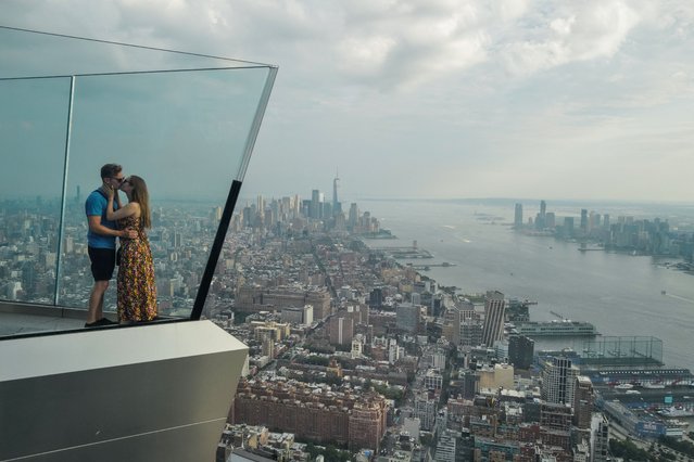 A couple kisses on the Edge at Hudson Yards observation deck with a view of Lower Manhattan in New York City on July 17, 2024. (Photo by Charly Triballeau/AFP Photo)