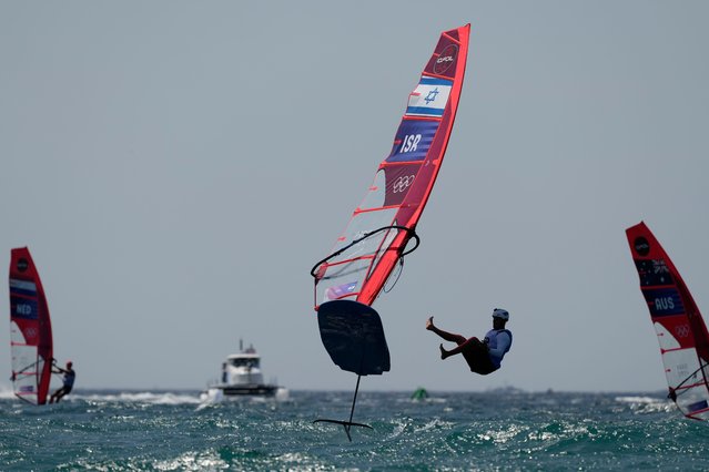 Tom Reuveny of Israel jumps from his iQFOiL windsurfer after finishing first in the final race to win the men's iQFOiL windsurfing class gold medal ahead of Grae Morris of Australia and Luuc van Opzeeland of the Netherlands during the 2024 Summer Olympics, Saturday, August 3, 2024, in Marseille, France. (Photo by Carolyn Kaster/AP Photo)