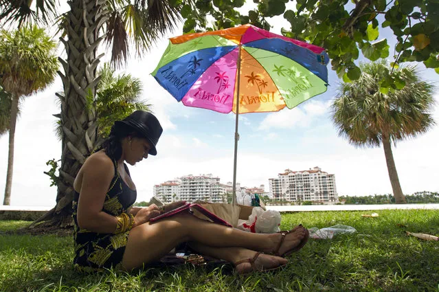 In this July 11, 2012, file photo, Airiannys Milford listens to music on her iPad as she sits in the shade at South Pointe Park in Miami Beach, Fla. (Photo by Alan Diaz/AP Photo)