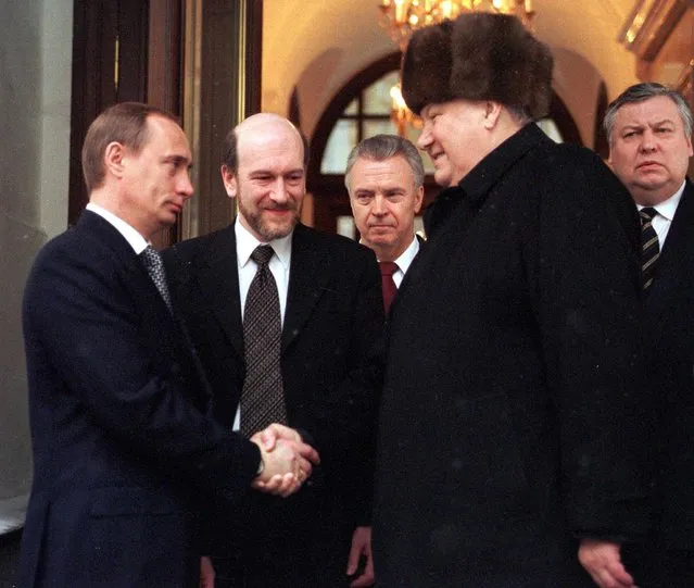 Retiring Russian President Boris Yeltsin (R) shakes hands with Prime Minister and acting President Vladimir Putin (L) as he leaves his office in the Kremlin 31 December 1999, as Presidential Administration head Alexander Voloshin (2D L) looks on (others unidentified). Yeltsin earlier announced his resignation, stipulating that Putin, under the Russian constitution, would run the county as acting president until elections in March 2000. (Photo by William West/AFP Photo)
