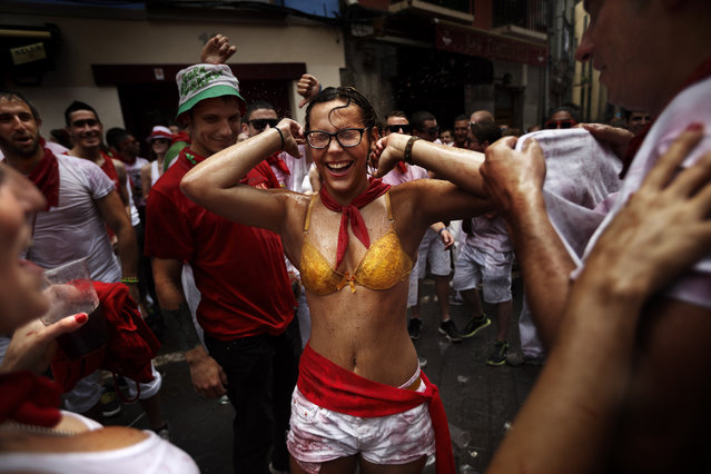 Revelers celebrate after the launch of the “Chupinazo” rocket, to celebrate the official opening of the 2014 San Fermin fiestas, in Pamplona, Spain, Sunday, July 6, 2014. Revelers from around the world kick off the festival with a messy party in the Pamplona town square, one day before the first of eight days of the running of the bulls glorified by Ernest Hemingway's 1926 novel “The Sun Also Rises”. (Photo by Daniel Ochoa de Olza/AP Photo)