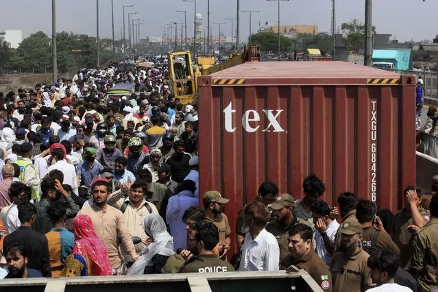 People cross a bridge on Ravi River which is closed for traffic due to shipping containers placed by authorities in an attempt to foil a planned protest of Pakistan's main opposition party, in Lahore, Pakistan, Tuesday, May 24, 2022. Pakistan's key opposition party led by recently ousted Prime Minister Imran Khan accused police of detaining hundreds of its supporters in raids that started early Tuesday. (Photo by K.M. Chaudary/AP Photo)