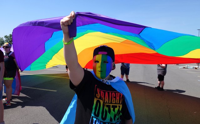 Hunter Kusak, of Syracuse, N.Y., holds up the rainbow flag during the Gay Pride Parade in Syracuse on Saturday, June 18, 2016. Thousands of people have attended a lesbian, gay, bisexual and transgender pride parade and festival in upstate New York, less than a week after a deadly attack at a gay nightclub in Orlando, Fla. (Photo by Michael Greenlar/The Syracuse Newspapers via AP Photo)