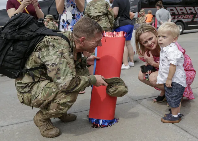 Capt. Steve Preston tries to get re-acquainted with his son Tommy as his wife Amber looks on, at a welcoming ceremony in Lincoln, Neb., Thursday, July 13, 2017, for about 90 Nebraska Army National Guard soldiers, members of the 1st Infantry Division Main Command Post-Operational Detachment, who had met their families for the first time after spending the last 9 months deployed in Iraq. (Photo by Nati Harnik/AP Photo)