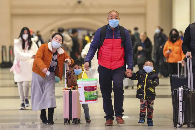 In this Tuesday, January 21, 2020, photo, travelers wearing face masks walk with their luggage at Hankou Railway Station in Wuhan in southern China's Hubei province. The U.S. on Tuesday reported its first case of a new and potentially deadly virus circulating in China, saying a Washington state resident who returned last week from the outbreak's epicenter was hospitalized near Seattle. (Photo by Chinatopix via AP Photo)