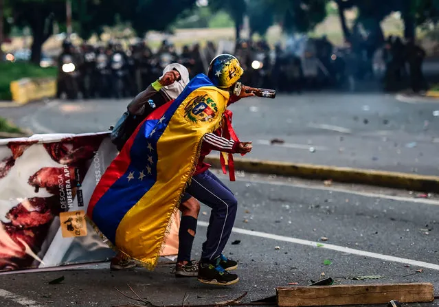 Opposition activists clash with the police during a protest against Venezuelan President Nicolas Maduro in Caracas, on July 18, 2017. Venezuela' s government on Tuesday defiantly brushed aside US President Donald Trump' s threat of economic sanctions by saying it will go ahead with the election of a controversial body to rewrite the country' s constitution. A 24- hour nationwide strike has been called for Thursday, launching what the opposition calls a “final offensive” to push Maduro out of office. (Photo by Ronaldo Schemidt/AFP Photo)