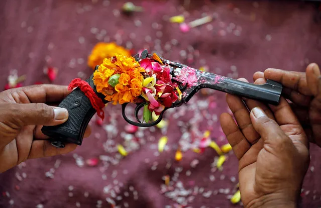 Police officers hold a revolver as they offer prayers to their weapons as part of a ritual at their headquarters on the occasion of Dussehra, or Vijaya Dashami, festival in Ahmedabad, India, October 8, 2019. (Photo by Amit Dave/Reuters)