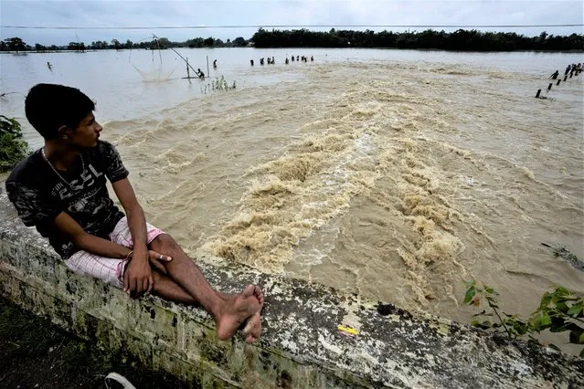 A boy watches people fishing in floodwaters in Korora village, west of Gauhati, India, Friday, June 17, 2022. (Photo by Anupam Nath/AP Photo)