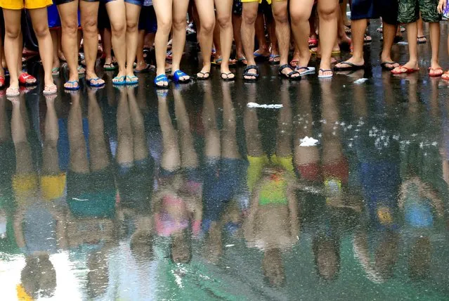 Residents are reflected on the wet street as they join in a water-splashing frenzy to honor their patron Saint John the Baptist's Feast Day in San Juan, Metro Manila, Philippines June 24, 2016. (Photo by Romeo Ranoco/Reuters)
