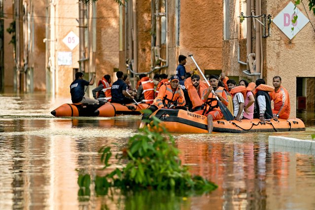 National Disaster Response Force (NDRF) and State Disaster Response Force (SDRF) personnel rescue residents from a flooded locality following heavy rainfall, in Bengaluru on October 22, 2024. Intense rain lashed southern India on October 16, with weather officials issuing a red alert warning of flash floods and landslides. (Photo by Idrees Mohammed/AFP Photo)