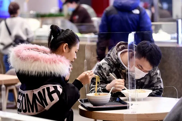 People eat at a restaurant using transparent boards to separate people, amid concerns about the spread of the COVID-19 coronavirus, in Shenyang in China's northeastern Liaoning province on March 2, 2020. The global death toll from the COVID-19 coronavirus epidemic surpassed 3,000 on March 2 after dozens more died at its epicentre in China and cases soared around the world, with a second fatality on US soil. (Photo by AFP Photo/China Stringer Network)