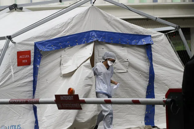 A doctor taking care of people with covid-19 symptoms exits a tent used as a waiting room set up in a courtyard of the Henri Mondor Hospital in Creteil, near Paris, Monday, March 9, 2020. The coronavirus is set to strike a severe blow to French growth in 2020, cutting several decimal points off a figure that may struggle to reach one percent, the finance minister said Monday. (Photo by Christophe Ena/AP Photo)