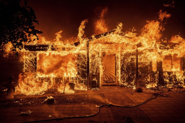 Flames consume a home on Triangle Rd. as the Oak Fire burns in Mariposa County, Calif., on Saturday, July 23, 2022. (Photo by Noah Berger/AP Photo)
