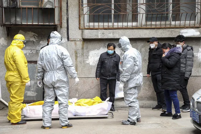 In this February 1, 2020, file photo, funeral home workers remove the body of a person suspected to have died from the coronavirus outbreak from a residential building in Wuhan in central China's Hubei Province. Skepticism about China’s reported coronavirus cases and deaths has swirled throughout the crisis, fueled by official efforts to quash bad news in the early days and a general distrust of the government. In any country, getting a complete picture of the infections amid the fog of war is virtually impossible. (Photo by Chinatopix via AP Photoi/File)