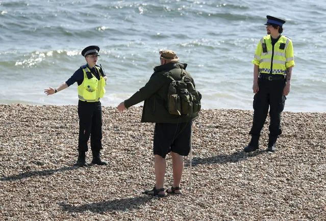 Police officers speak to a man as they patrol the beach in Brighton as the UK continues its lockdown to help curb the spread of coronavirus, in Brighton, England, Saturday April 25, 2020. (Photo by Gareth Fuller/PA Wire via AP Photo)