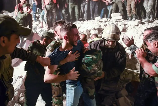 A man reacts as rescuers search for victims and survivors amidst the rubble of a building that collapsed in Syria's northern city of Aleppo, on September 7, 2022. Ten people were killed when a five-story building collapsed in the Ferdaws neighbourhood of Aleppo, state media said. “The bodies of six women, three children and a man were recovered, while a child and a woman were rescued from under the rubble and taken to hospital”, the official SANA news agency said. (Photo by AFP Photo/Stringer)