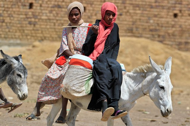Sudanese women ride their donkeys in the village of al-Laota, about 70 kilometres southwest of Sudan's capital Khartoum on May 28, 2022. Impoverished Sudan has for years been grappling with a grinding economic crisis, which deepened after last year's military coup prompted Western governments to cut crucial aid. The October coup derailed a fragile transition put in place following the 2019 ouster of president Omar al-Bashir. (Photo by Ashraf Shazly/AFP Photo)