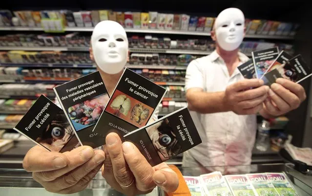 Tobacconists display images which will be used for cigarette packs during a protest in a French “Tabac” in Cagnes-sur-Mer, France, September 8, 2015. France's tobacconists are protesting plans to force cigarette companies to use plain, unbranded packaging, as part of anti-smoking legislation. Slogans read “smoking causes blindness, smoking causes peripheral vascular disease, smoking causes cancer”. (Photo by Eric Gaillard/Reuters)