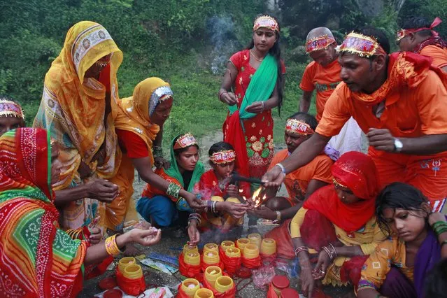 Hindu devotees perform rituals during the Bol Bom pilgrimage, on the outskirts of Kathmandu, Nepal, Monday, August 8, 2016. During this pilgrimage, devotees walk miles barefooted before offering water collected from Bagmati river, at the Pashupatinath temple in Katmandu. Shravan Somwar or Monday of Hindu calendar month of Shravan is considered auspicious for offering prayers to Lord Shiva, the god of destruction. (Photo by Niranjan Shrestha/AP Photo)