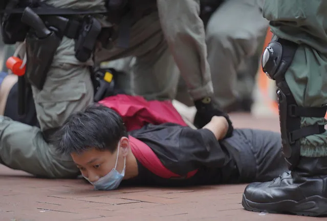 A protester is detained by riot police during a demonstration against Beijing's national security legislation in Causeway Bay in Hong Kong, Sunday, May 24, 2020. Hong Kong police fired volleys of tear gas in a popular shopping district as hundreds took to the streets Sunday to march against China's proposed tough national security legislation for the city. (Photo by Vincent Yu/AP Photo)