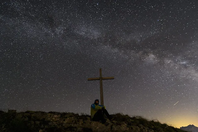 epaselect epa05448414 A person is leaning against a cross below of Milky Way on the Tour d'Ai mountain (2331 m) above Leysin, Switzerland, 29 July 2016. (Photo by Anthony Anex/EPA)