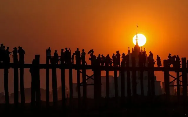 Visitors walk along the long wooden U Bein Bridge that connects the two banks of Taungthaman Lake as the sun sets Wednesday, March 11, 2020, in Mandalay, central Myanmar. (Photo by Thein Zaw/AP Photo)