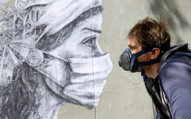 French street artist Ardif poses in front of his artwork to pay tribute to caregivers and medical workers due to the epidemic of coronavirus (COVID 19) on May 12, 2020 in Paris, France. The Coronavirus (COVID-19) pandemic has spread to many countries across the world, claiming over 286,000 lives and infecting over 4.1 million people. (Photo by Chesnot/Getty Images)