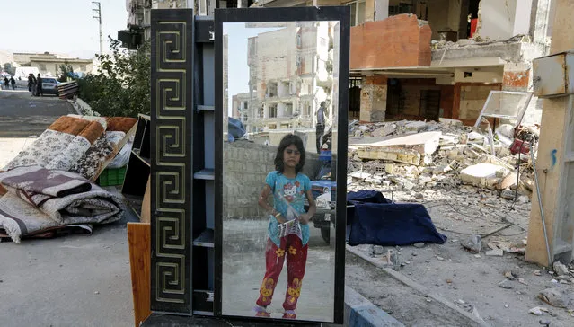 An Iranian girl looks through a salvaged mirror from a damaged building in the town of Sarpol-e Zahab in the western Kermanshah province near the border with Iraq, on November 14, 2017, following a 7.3-magnitude earthquake that left hundreds killed and thousands homeless two days before. (Photo by Atta Kenare/AFP Photo)