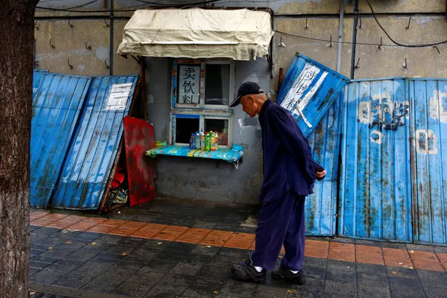 An elderly man walks past a shops selling drinks through a window in Beijing, China, August 18, 2016. (Photo by Thomas Peter/Reuters)