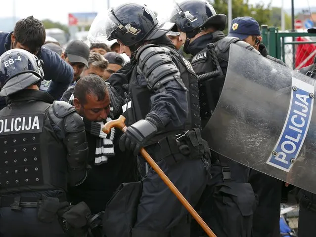 Police helps a migrant with a walking stick to pass a police cordon at the Croatia-Slovenia border crossing at Bregana, Croatia, September 20, 2015. (Photo by Laszlo Balogh/Reuters)
