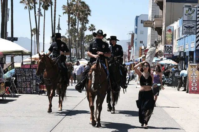 Los Angeles Police officers on horseback patrol the strand along Venice Beach on Friday, July 3, 2020, in Los Angeles. Gov. Gavin Newsom is urging Californians to use common sense over the Fourth of July weekend by wearing face masks and avoiding traditional gatherings with family and friends. (Photo by Richard Vogel/AP Photo)