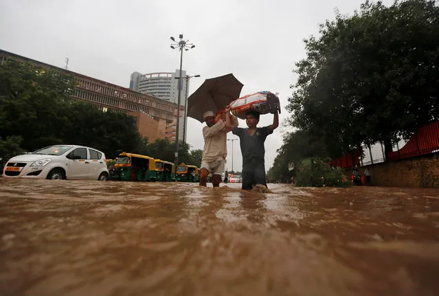 A man and his son wade through a flooded street during heavy rains in New Delhi, India, August 29, 2016. (Photo by Adnan Abidi/Reuters)